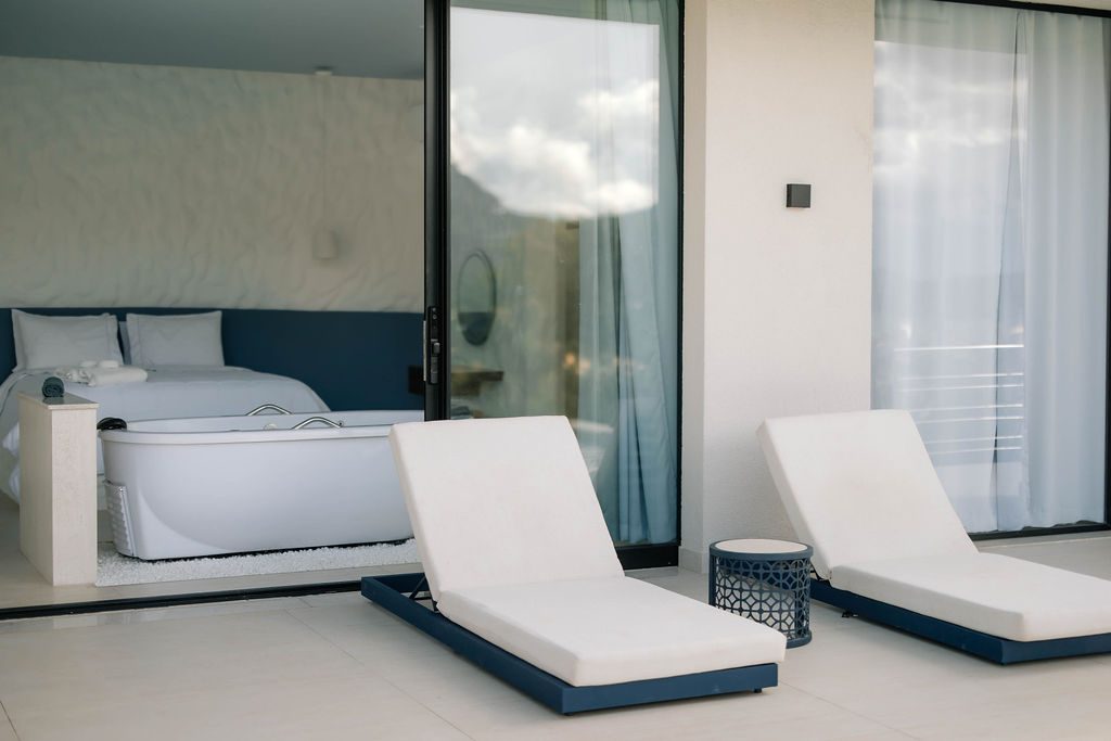 Varanda do Loft Grécia com espreguiçadeiras diante da cama