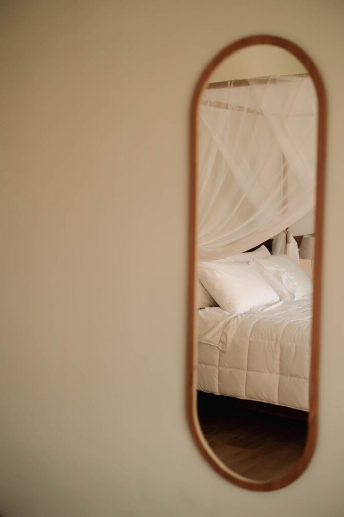 Espelho de arco refletindo a cama com dossel do Loft Maldivas