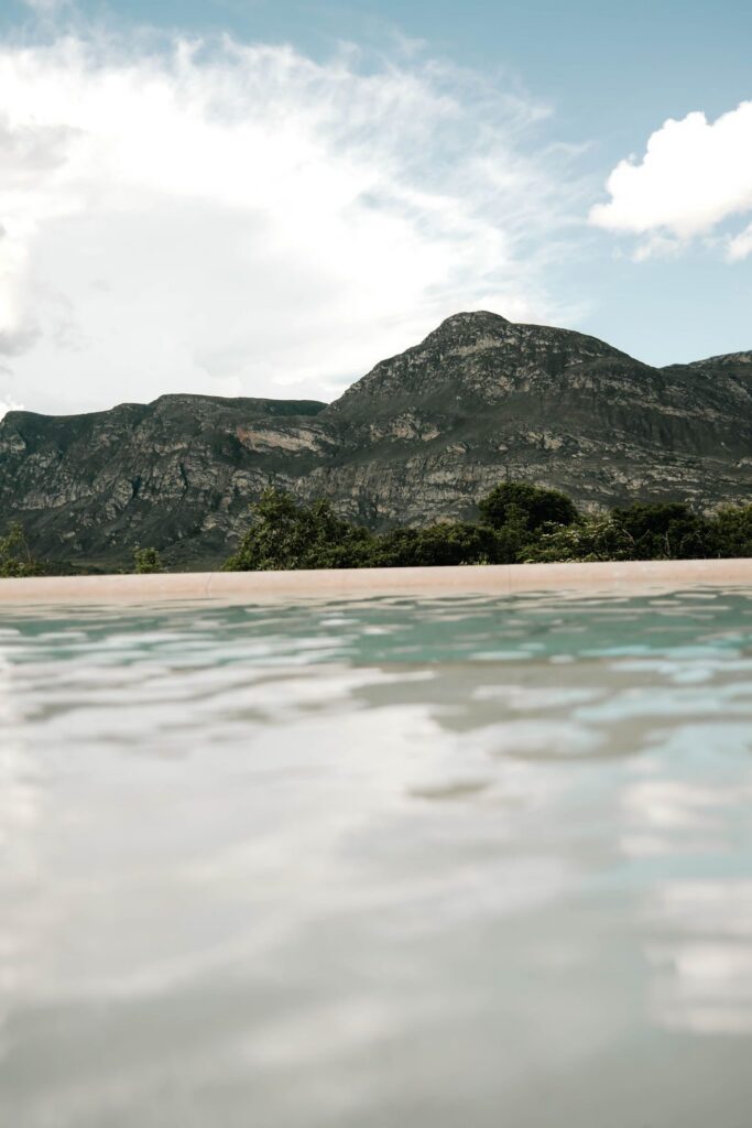 Borda da piscina no nível da água com a serra ao fundo